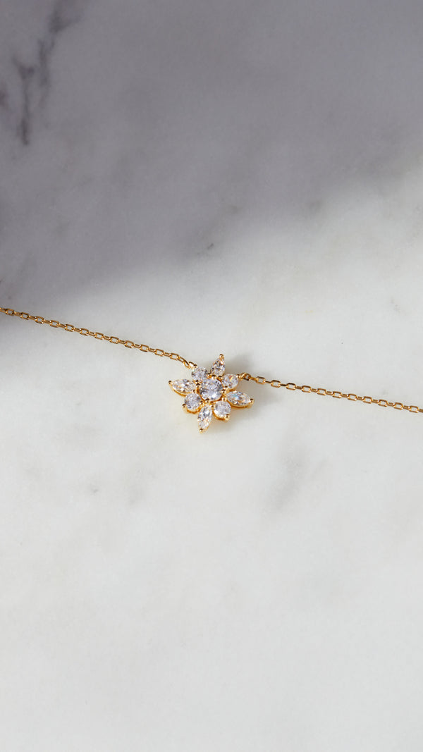 Delicate gold chain necklace with round cut stones in bezel setting. Features a cluster of Round and Marquise cut stones resembling a flower.