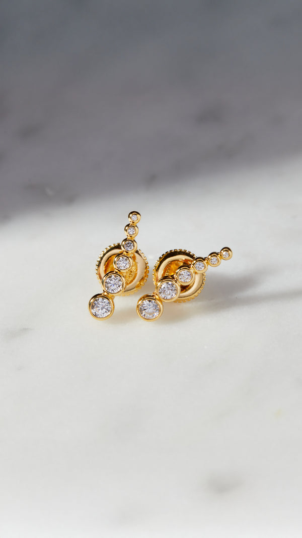 Ear climber gold earrings for women featuring graduated round stones. 