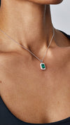 Classic sterling silver pendant necklace featuring a hand-cut emerald green stone and delicate border settings. 