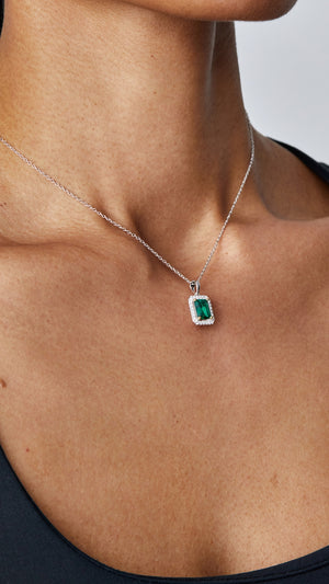 Classic sterling silver pendant necklace featuring a hand-cut emerald green stone and delicate border settings. 