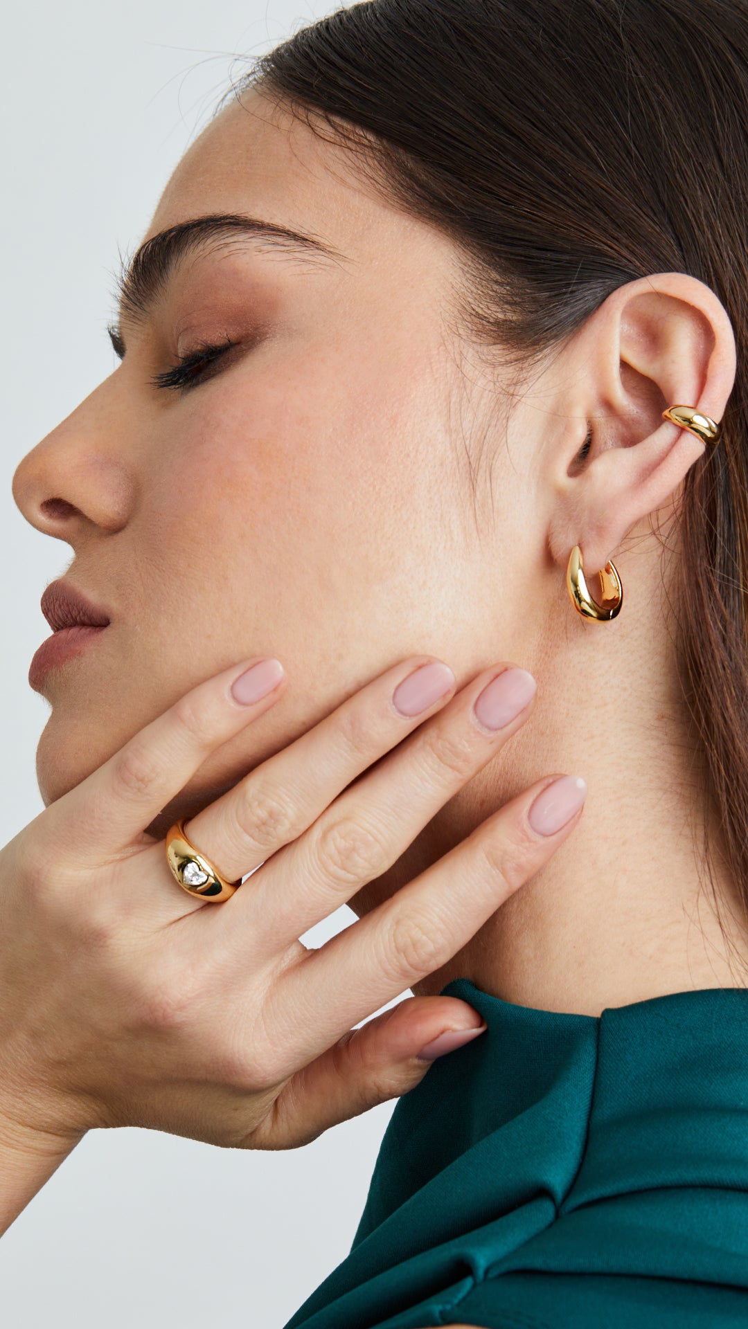 A contemporary gold signet ring, featuring a polished heart-shaped gemstone for a sleek and modern finish. Paired here with gold teardrop hoops and matching gold ear cuff.