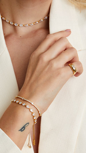 Gold stacking ring for women paired with gold tennis bracelets.